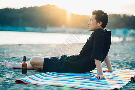 坐在海滩上看日落的成年男子图片