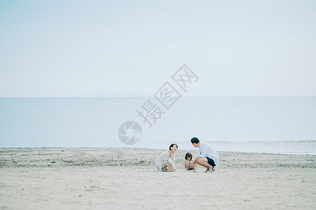 蹲下女男人享受海水浴的家庭图片