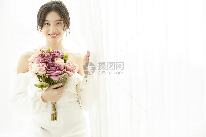 穿着婚纱的美丽新娘抱着手捧花图片
