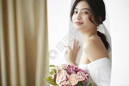 穿着婚纱的美丽新娘抱着手捧花图片