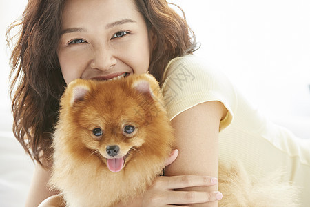 年轻女子在床上开心的抱着小狗图片