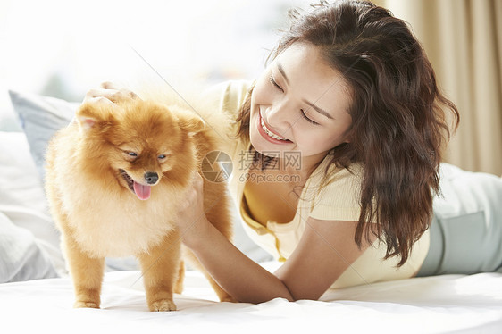 年轻女子在床上开心的抱着小狗图片
