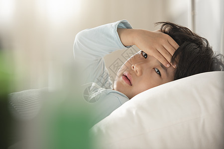 感冒生病的小男孩躺在床上图片