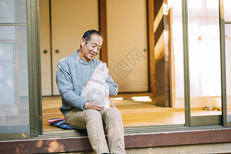 抱着白色博美犬的老年男性图片