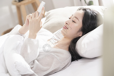 躺在床上玩手机的青年女子图片