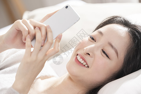 青年女子躺着玩手机图片
