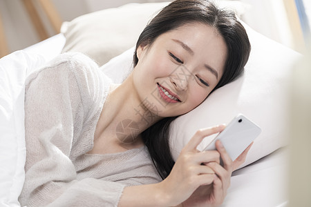 青年女子躺在床上玩手机图片