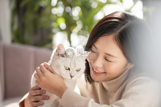 抱着宠物猫咪开心的年轻女子图片