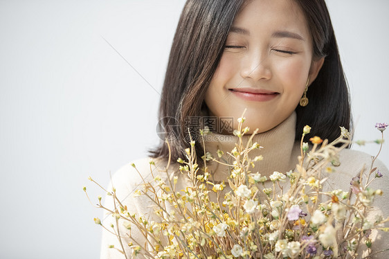 美容年轻女遵守手捧花的年轻女子的画像图片