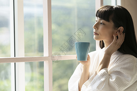 窗户旁喝咖啡的青年女子图片