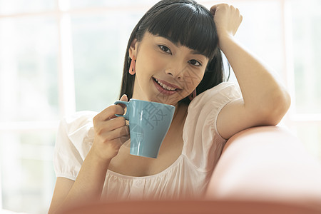 沙发上喝咖啡的年轻女子图片