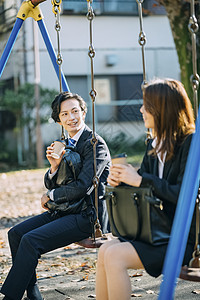 公园秋千上喝咖啡聊天的商务人士图片