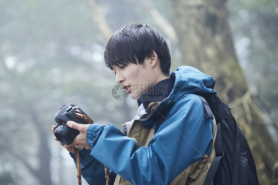 森林徒步拿着相机的青年男性图片