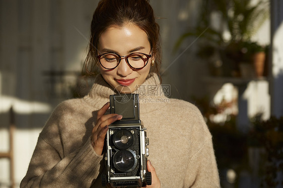 拿着相机拍照片的年轻女子图片