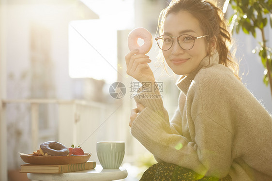 拿着甜甜圈微笑的年轻女子图片