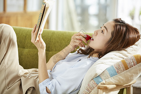 居家阅读吃草莓的年轻女子图片