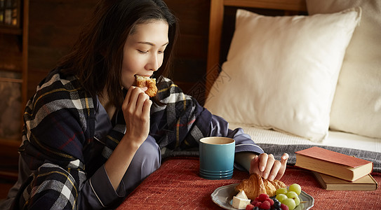 青年女子在卧室里吃早餐高清图片