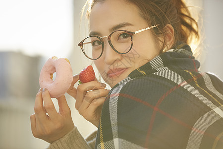 女孩和草莓拿着甜甜圈和草莓微笑的年轻女子背景