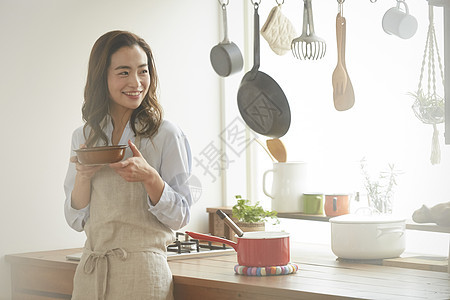 厨房里端着食物的年轻女子图片