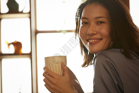 拿着咖啡微笑的青年女子图片