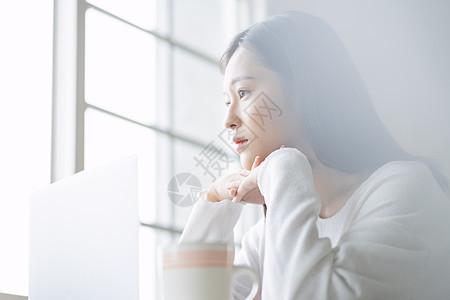 看向窗外思考的年轻女子图片