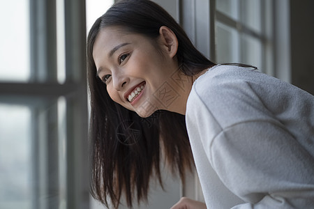 看着窗外开心的年轻女子图片