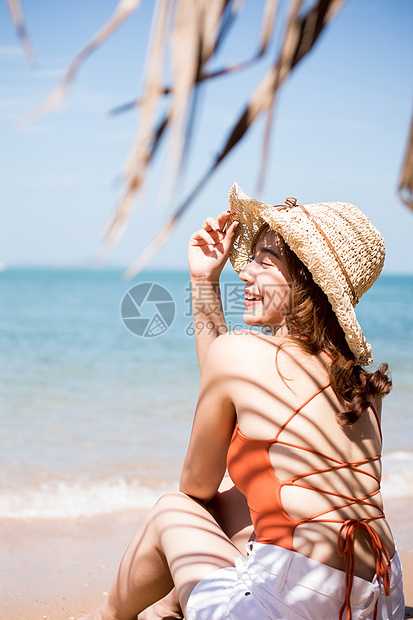 蓝色的海洋乐趣旅游泳装的一名妇女坐在海滩图片