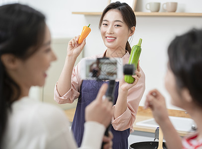 拍摄烹饪做菜短视频的年轻女子图片