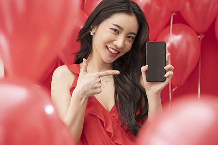 在红色气球背景下使用手机的女性图片