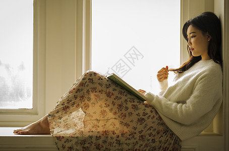 坐在窗边看书的青年女子图片