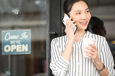 拿着咖啡接听电话的商务女性图片