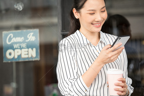 看着手机微笑的商务女青年图片