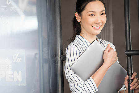 抱着笔记本电脑微笑的商务女性图片