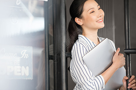 抱着笔记本电脑微笑的年轻女子图片