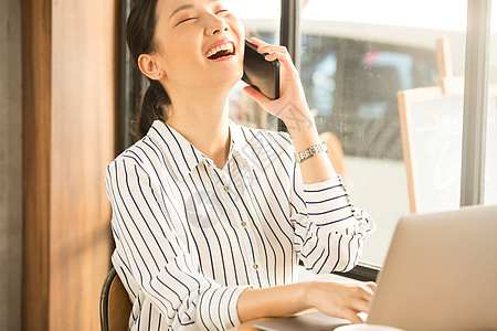 咖啡馆接听电话大笑的青年女性图片