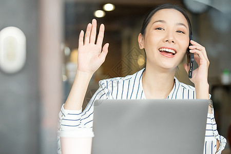 接听电话伸手打招呼的商务女性图片