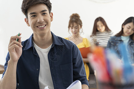 拿着笔微笑的男大学生图片