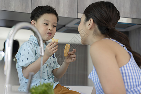 母亲和男孩在厨房里吃东西图片