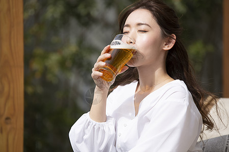 户外喝啤酒的年轻女子图片