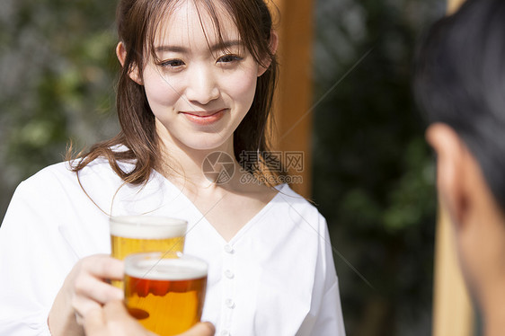 喝啤酒干杯的年轻女子图片