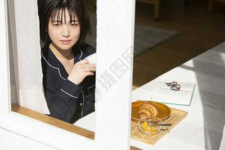 坐在窗边独自吃早餐的年轻女子图片