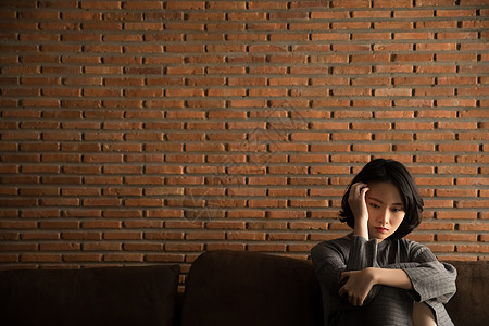 抱膝坐在沙发上的孤独女性图片素材