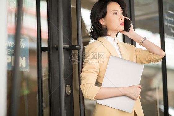 商务女性抱着笔记本电脑打电话图片