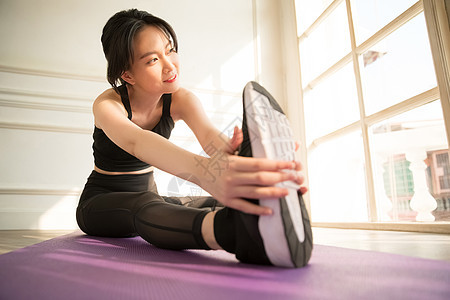 室内瑜伽拉伸的年轻女子图片