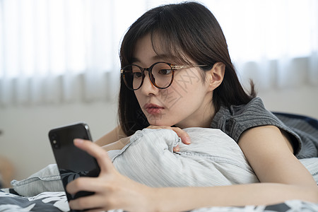 趴着玩手机的年轻女子图片素材