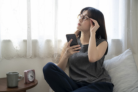 居家拿着手机的年轻女子图片