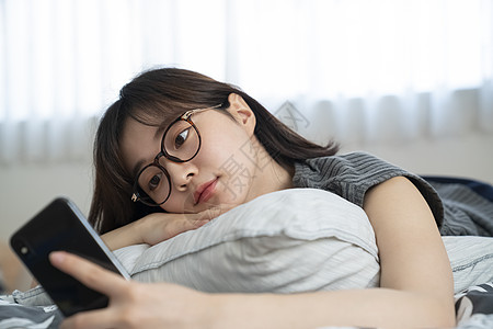 居家独自玩手机的年轻女子图片