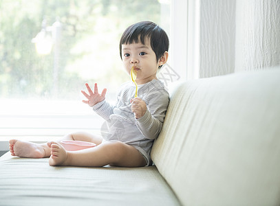 坐在沙发上拿着勺子的小孩图片