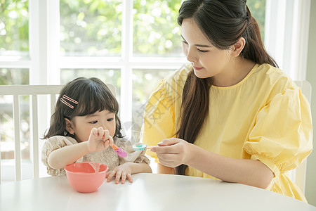 照顾女儿喂饭的母亲背景图片