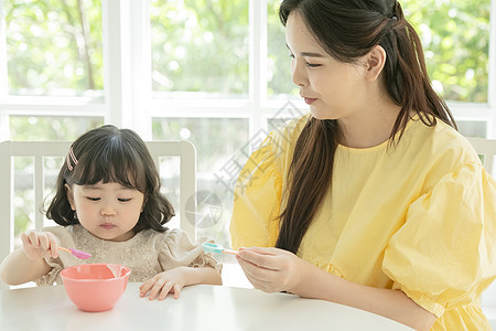 照顾女儿喂饭的母亲背景图片